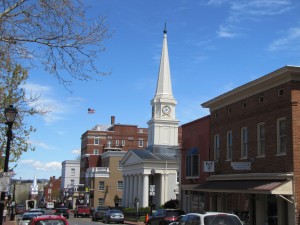 a street view with brick buildings and a white building with a steeple