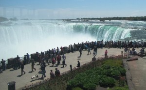 Niagara Falls and a number of people walking and standing along the walkway next to it