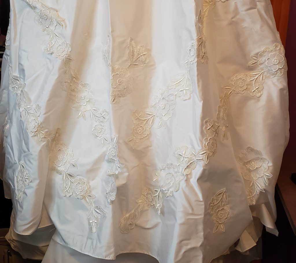 The skirt of a white wedding dress with floral appliques